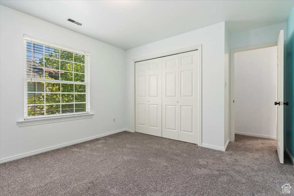 Unfurnished bedroom featuring carpet flooring, baseboards, and a closet
