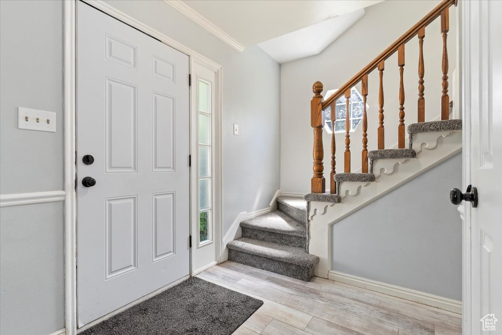 Entryway featuring wood finished floors, stairs, plenty of natural light, ornamental molding, and baseboards