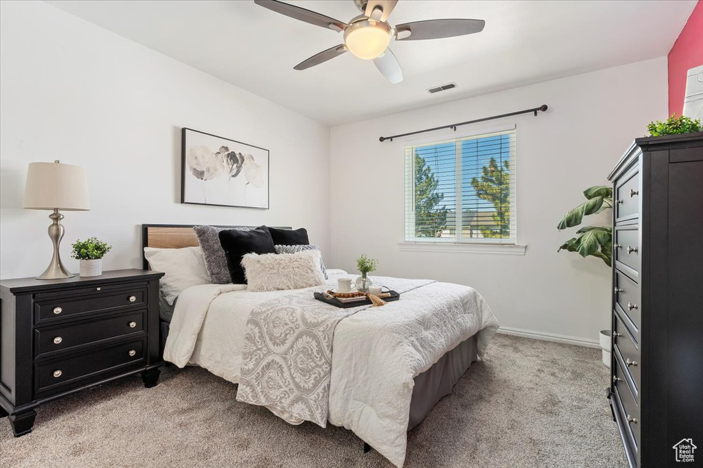 Bedroom with light carpet, a ceiling fan, and baseboards