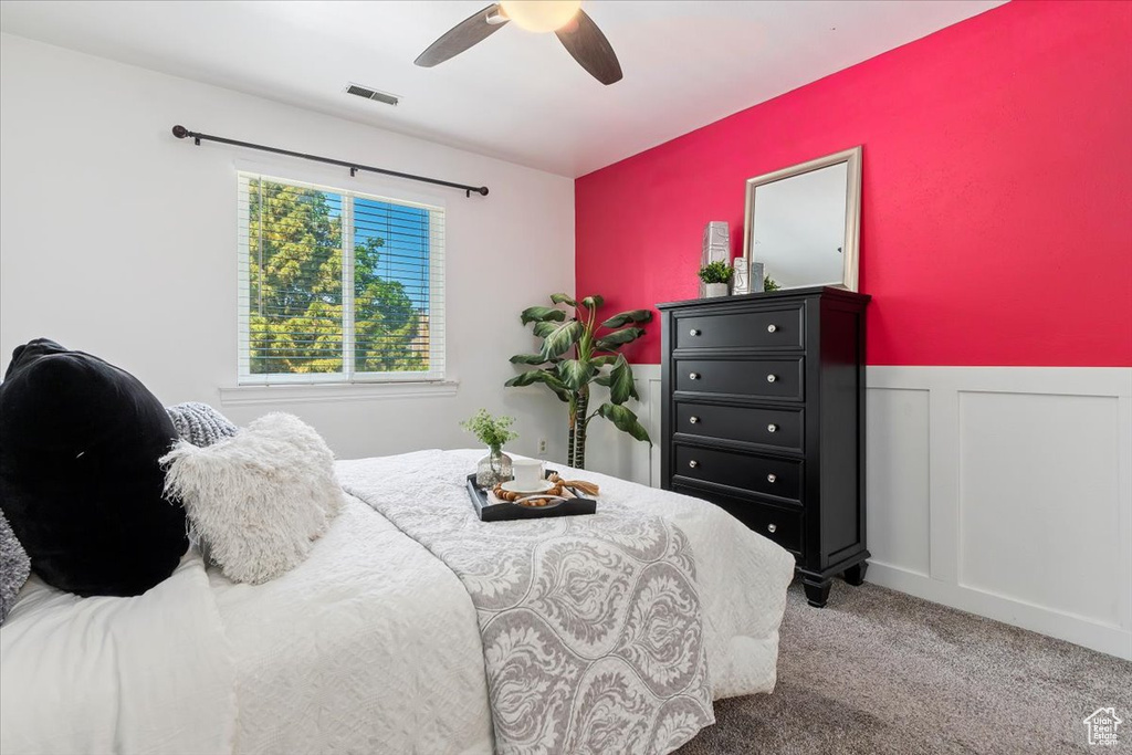 Carpeted bedroom with a wainscoted wall and a ceiling fan