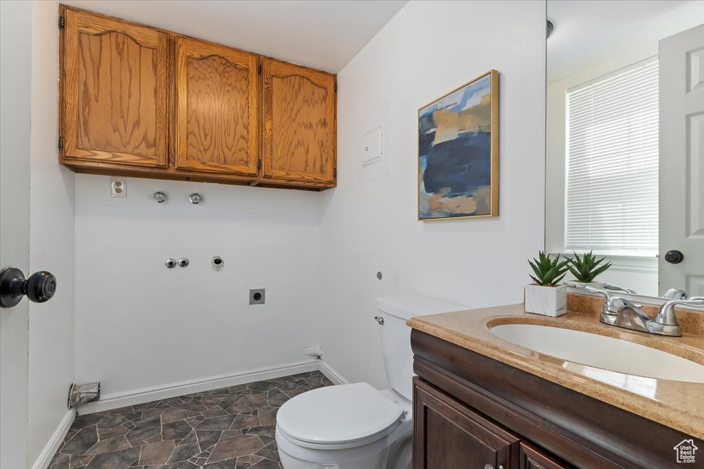 Half bathroom with toilet, baseboards, vanity, and stone finish flooring