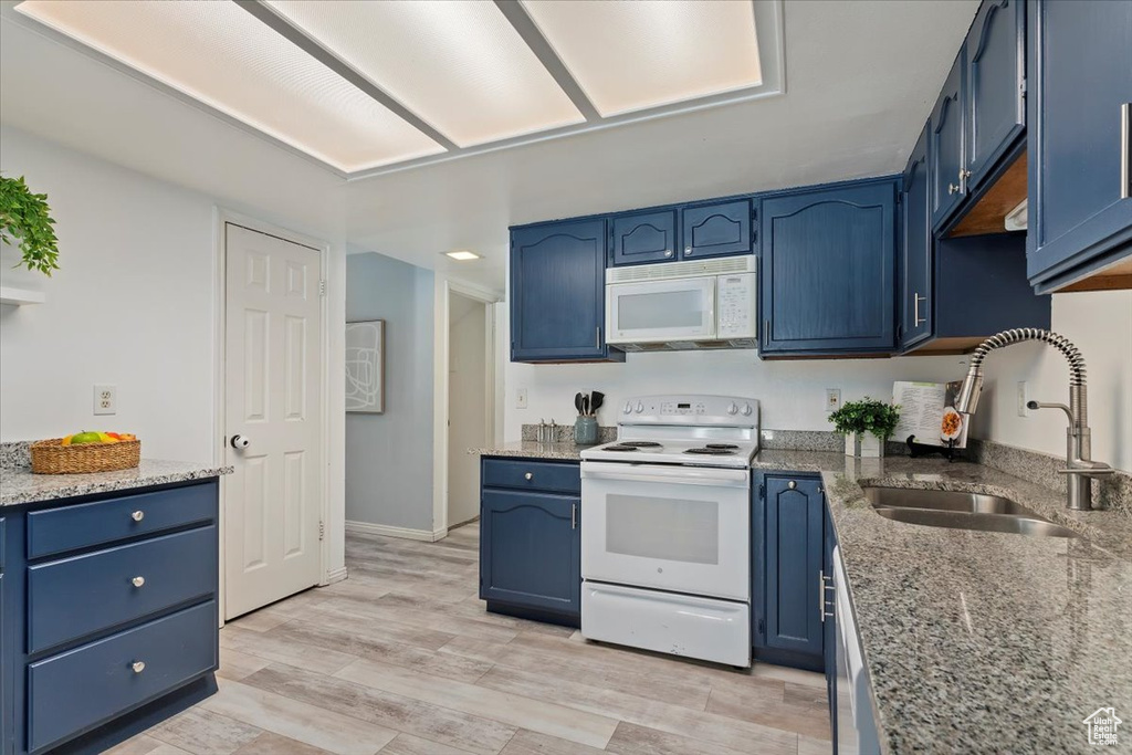 Kitchen with white appliances, a sink, and blue cabinets