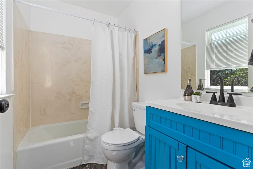 Bathroom with healthy amount of natural light, vanity, toilet, and shower / bath combo with shower curtain