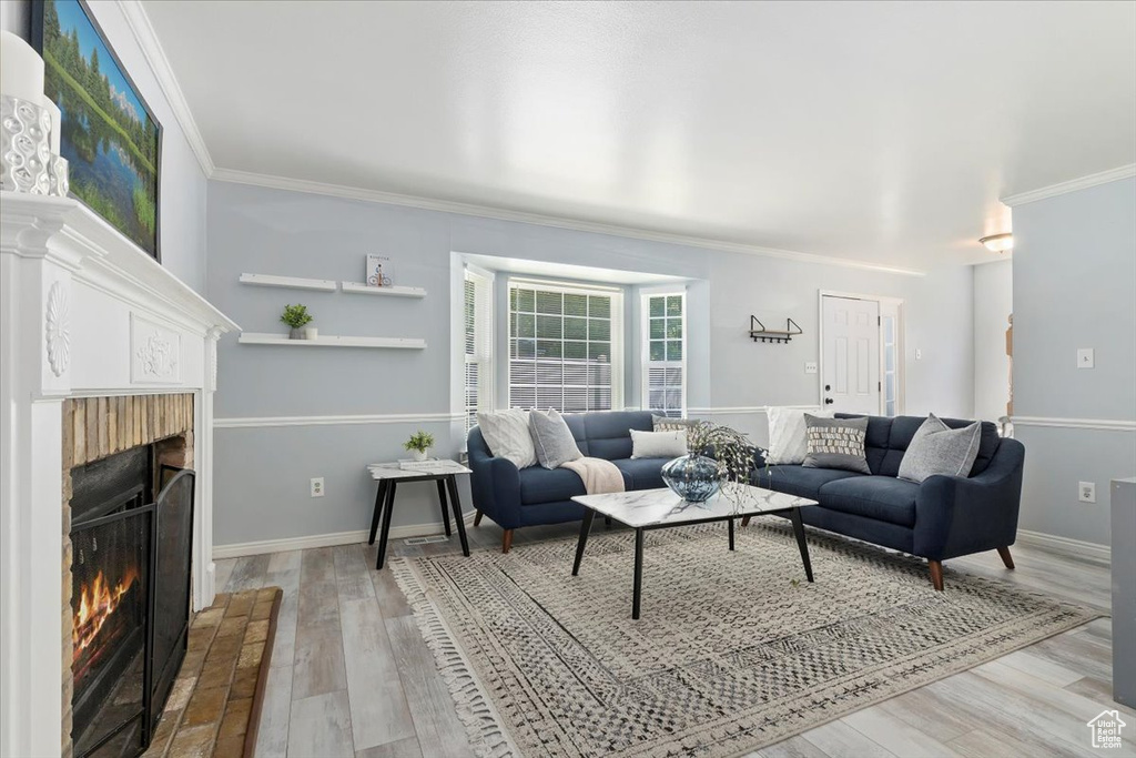 Living area featuring a warm lit fireplace, ornamental molding, wood finished floors, and baseboards