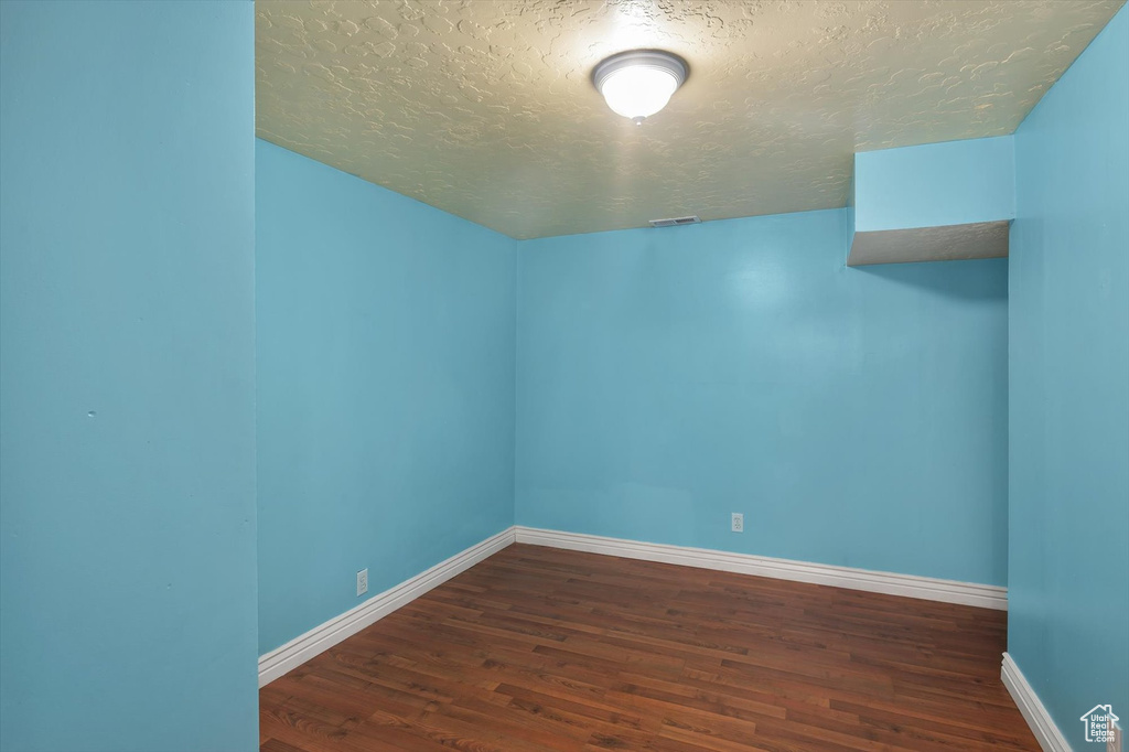 Bonus room with a textured ceiling, dark wood-style flooring, and baseboards