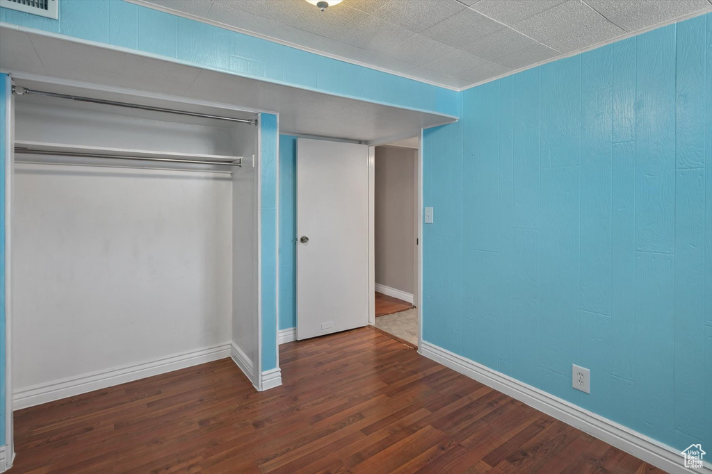 Unfurnished bedroom with a closet, wood finished floors, and ornamental molding