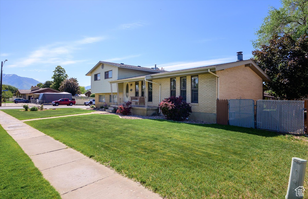 Tri-level home with a porch, brick siding, and a mountain view