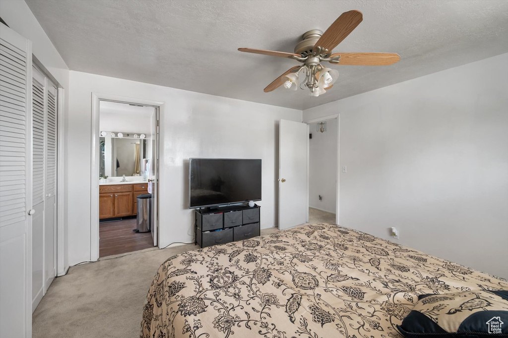 Bedroom with light colored carpet, ensuite bath, a ceiling fan, and a closet