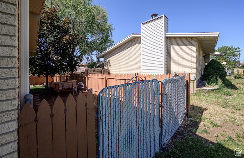 View of home\\\\\\\\\\\\\\\'s exterior featuring a gate, brick siding, and a chimney