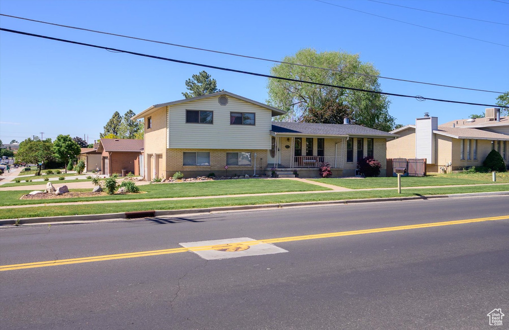 View of front of property with covered porch, a front lawn, and brick siding