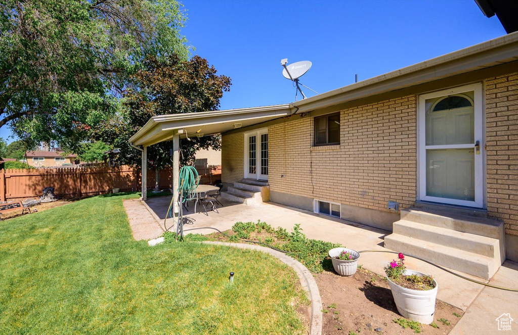Rear view of property featuring entry steps, a patio area, brick siding, and french doors