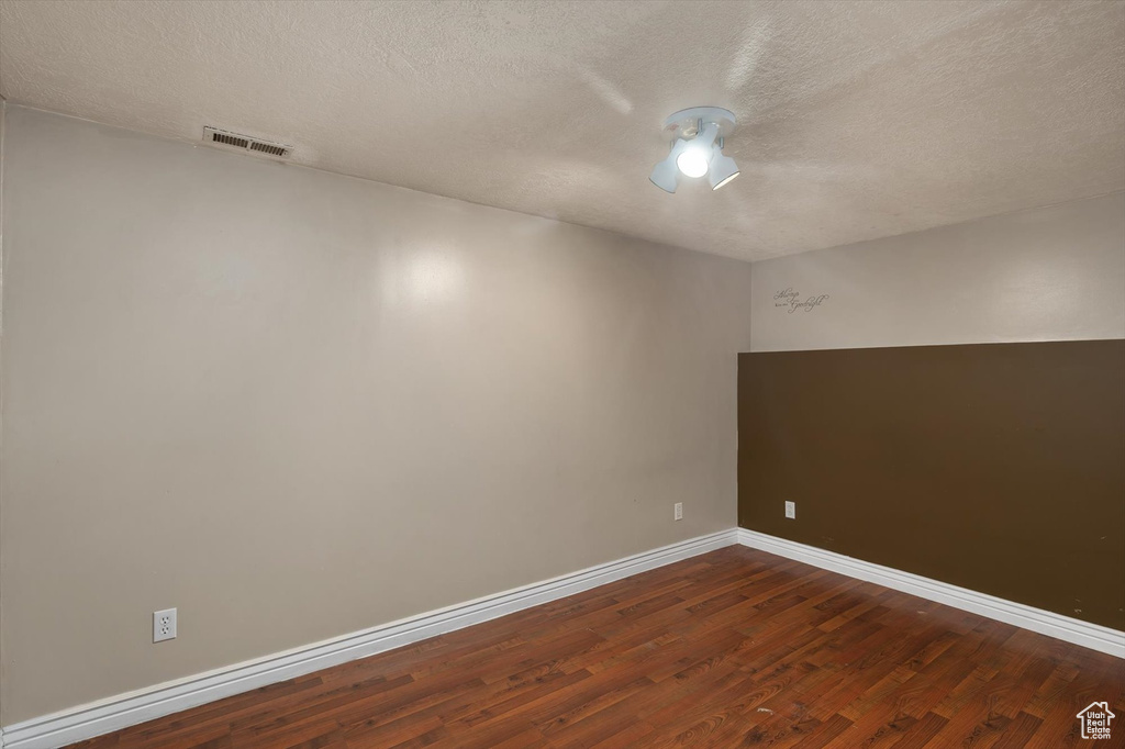Unfurnished room with dark wood-type flooring, a textured ceiling, and baseboards