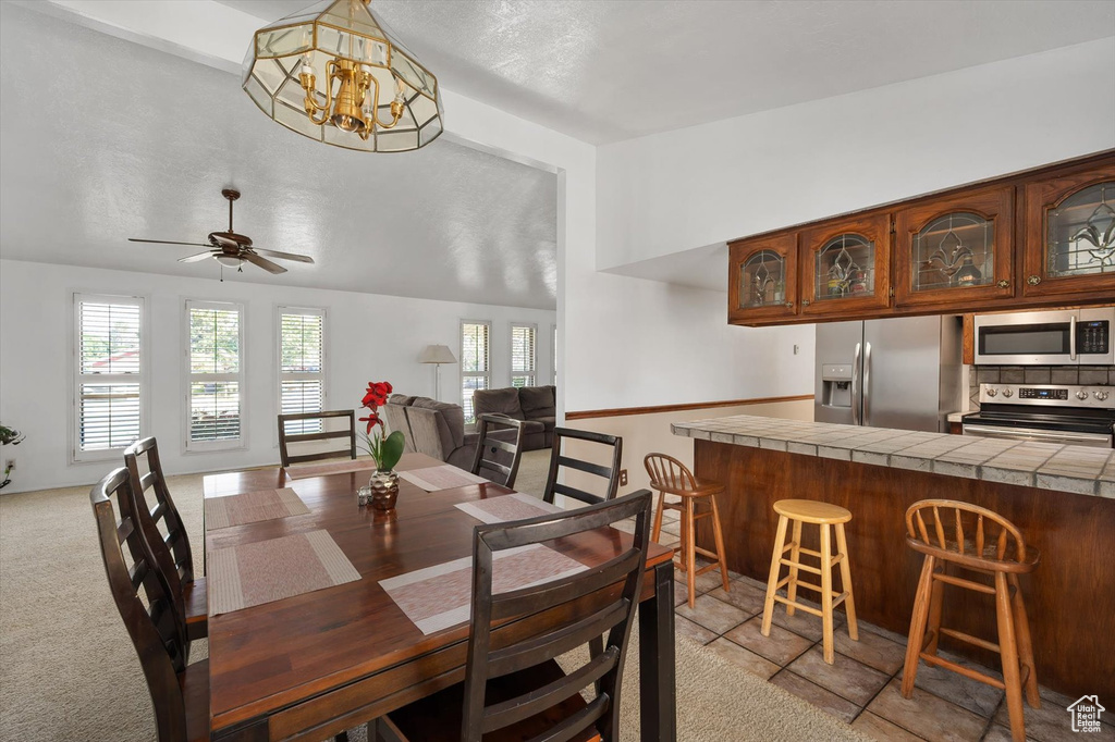 Dining area featuring a chandelier, ceiling fan, and light colored carpet