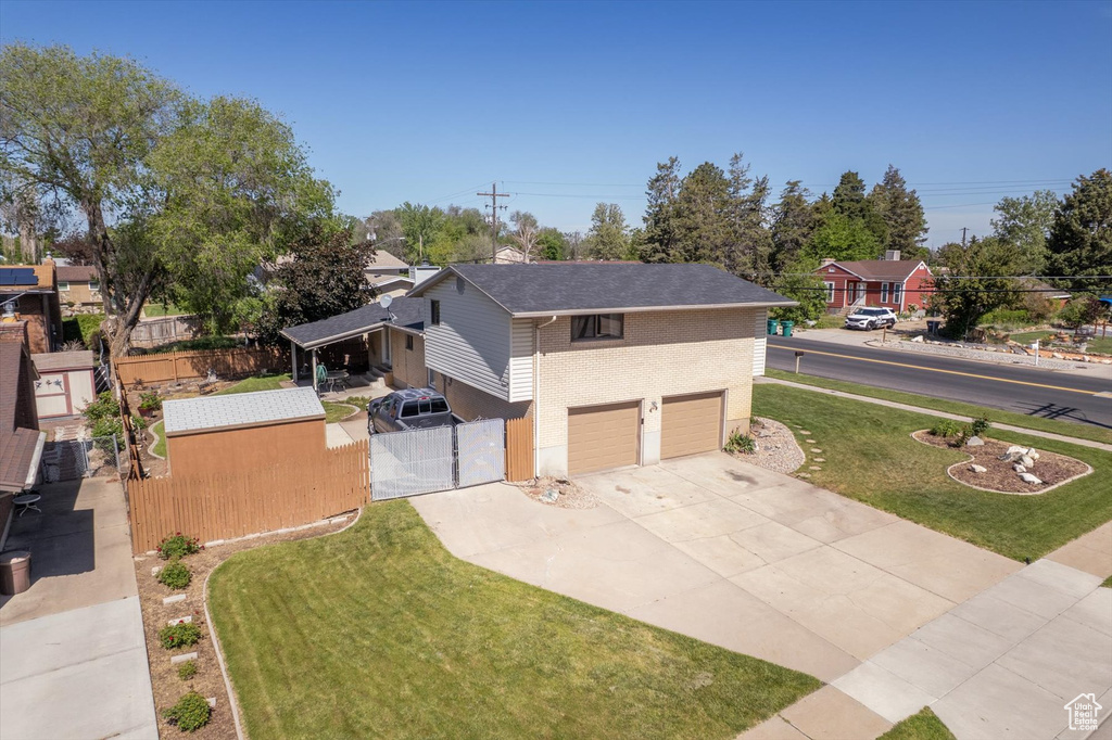 View of front of property with a gate, concrete driveway, an attached garage, and brick siding