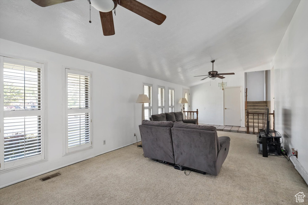 Carpeted living room with ceiling fan and plenty of natural light