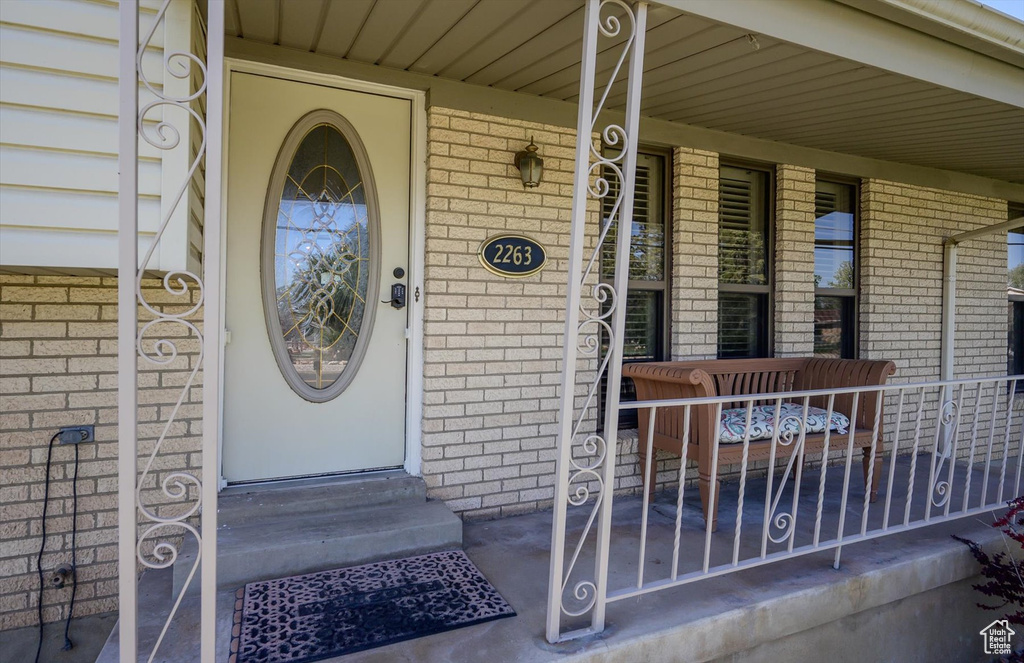 Doorway to property featuring brick siding and covered porch