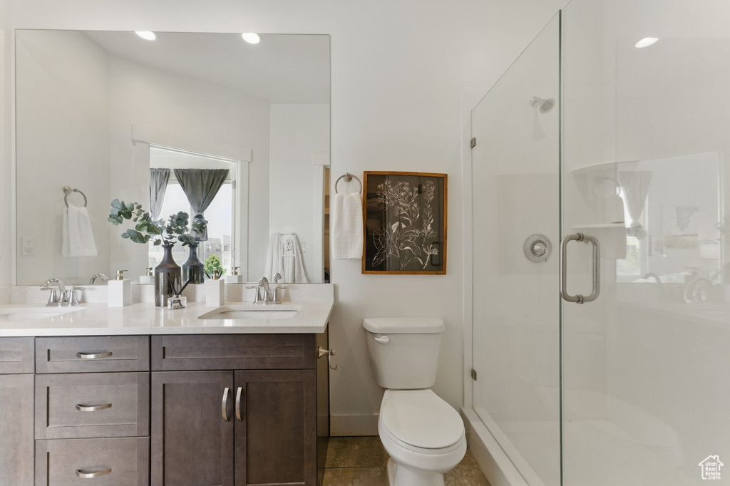 Full bathroom with double vanity, a shower stall, toilet, and tile patterned floors