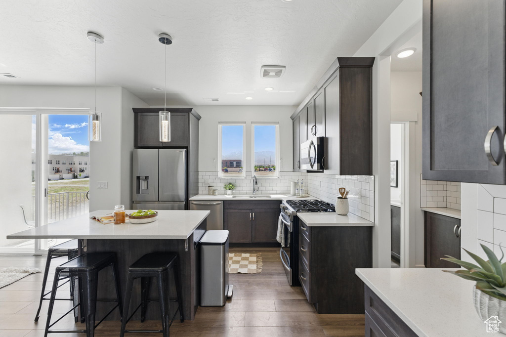 Kitchen featuring appliances with stainless steel finishes, plenty of natural light, a kitchen bar, decorative backsplash, and recessed lighting