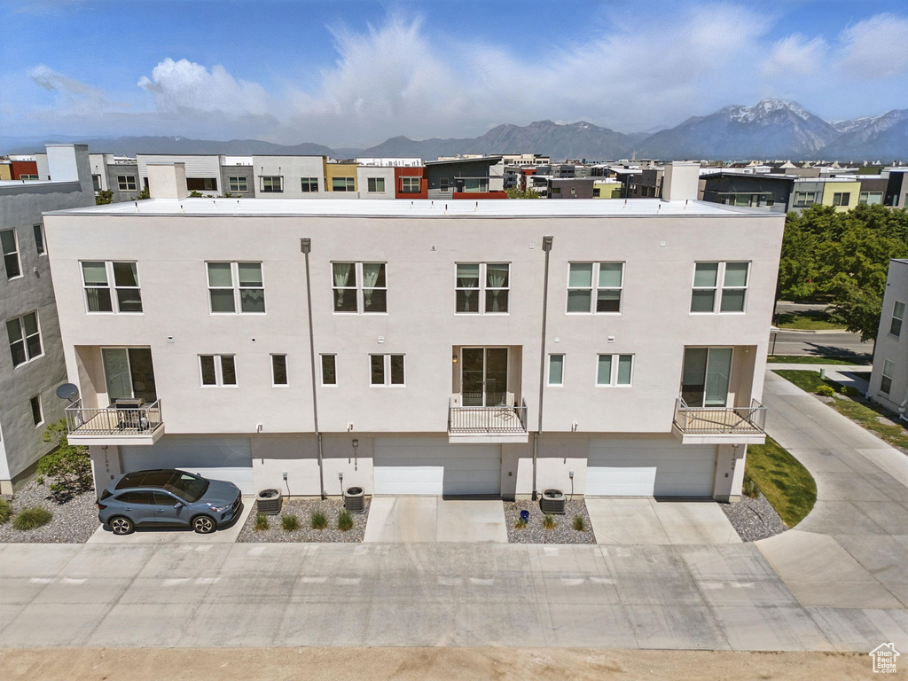View of building exterior with a mountain view, a garage, and concrete driveway
