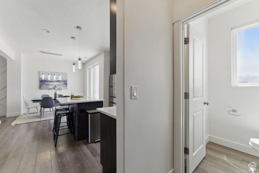 Kitchen featuring dark wood finished floors, light countertops, a breakfast bar area, a kitchen island, and decorative light fixtures