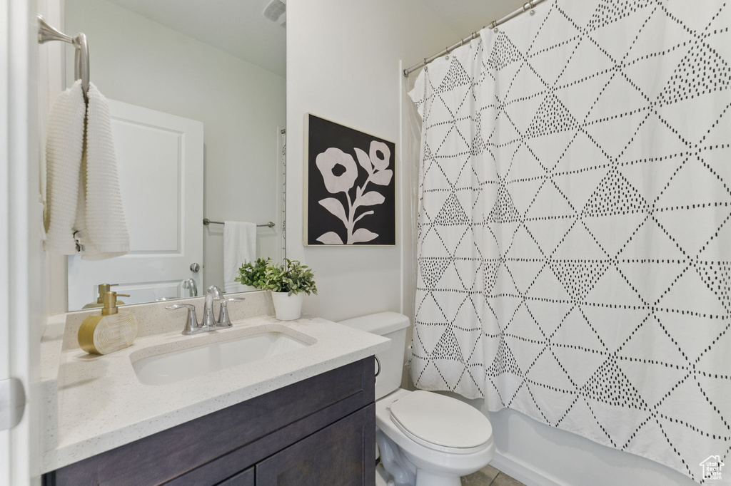 Bathroom featuring toilet, vanity, and shower / bath combo with shower curtain