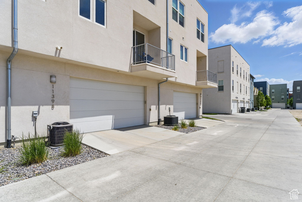 View of property featuring central air condition unit, a residential view, an attached garage, and concrete driveway