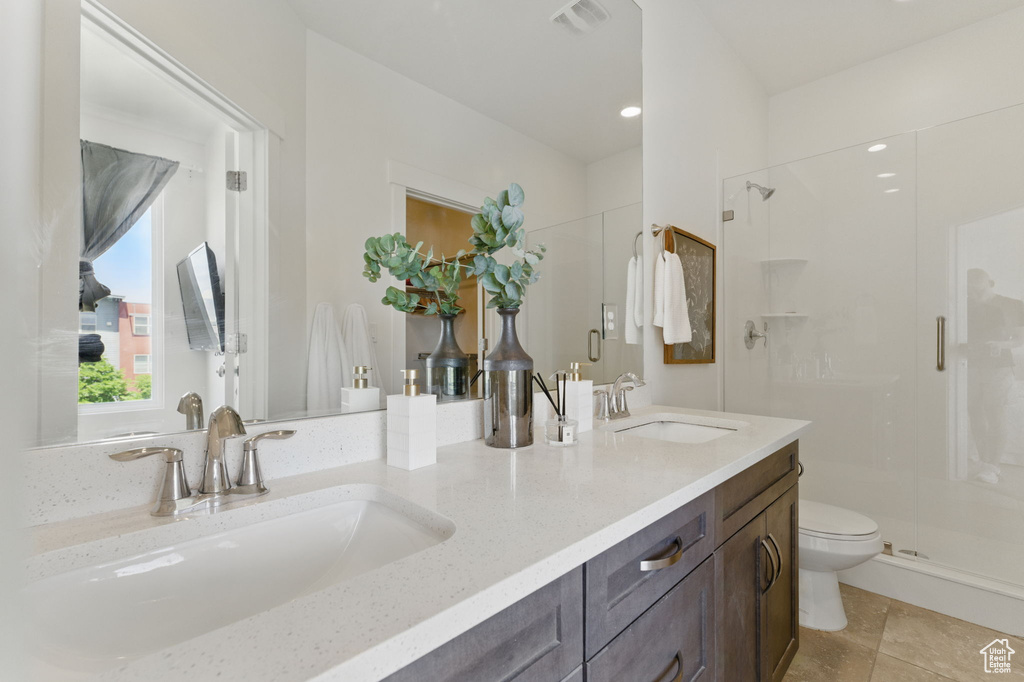 Bathroom featuring a stall shower, toilet, and double vanity