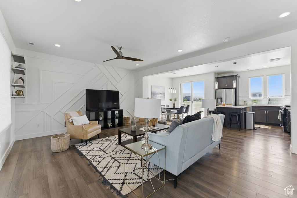Living room with plenty of natural light, dark wood-type flooring, ceiling fan, a decorative wall, and recessed lighting