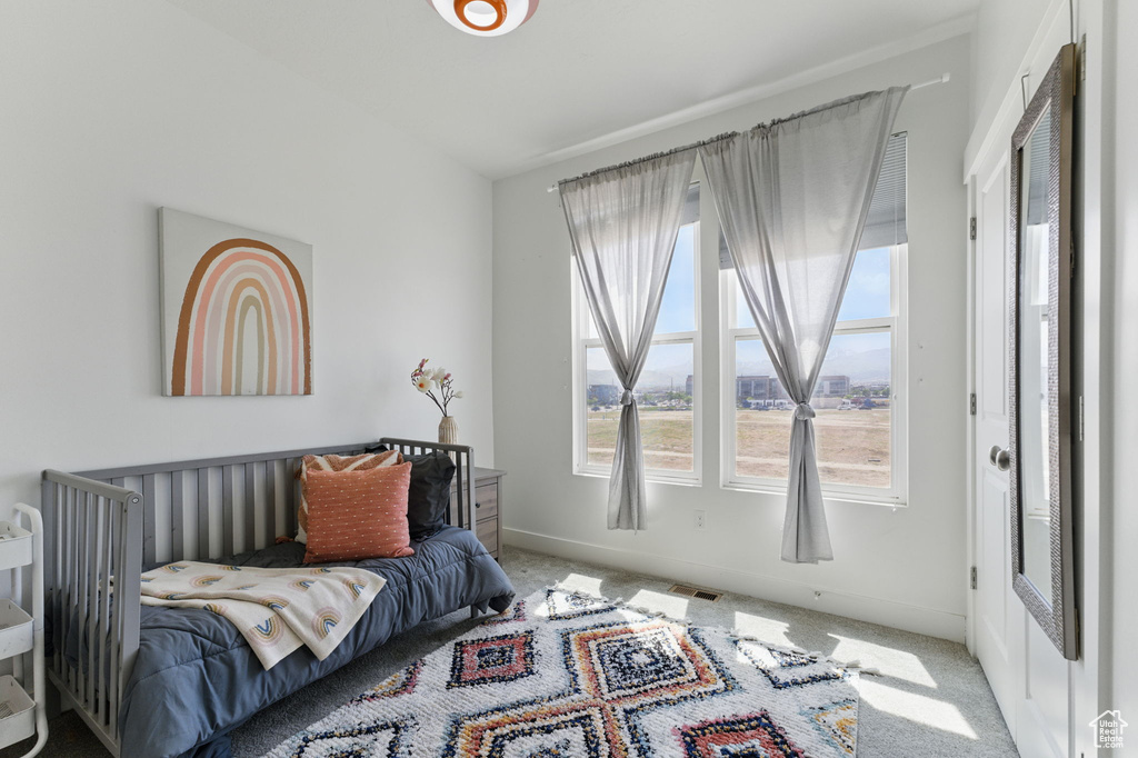 Carpeted bedroom with multiple windows and baseboards