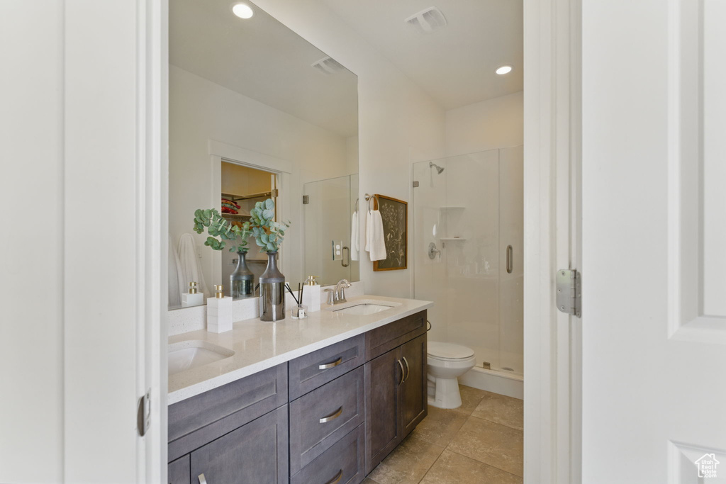 Full bathroom featuring a shower stall, toilet, double vanity, tile patterned flooring, and a walk in closet