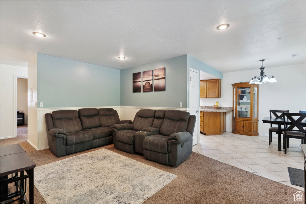 Living room featuring a chandelier, light tile patterned flooring, wainscoting, light colored carpet, and recessed lighting