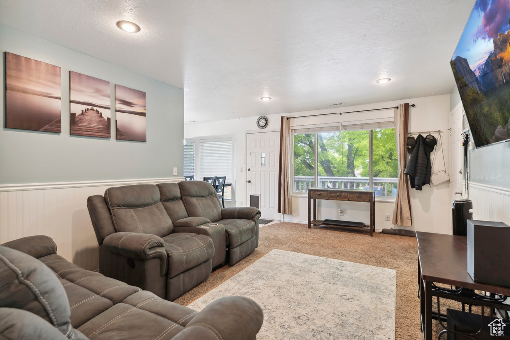 Living area featuring plenty of natural light, light colored carpet, and a wainscoted wall
