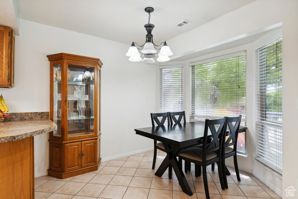 Dining space with a chandelier, light tile patterned floors, and baseboards