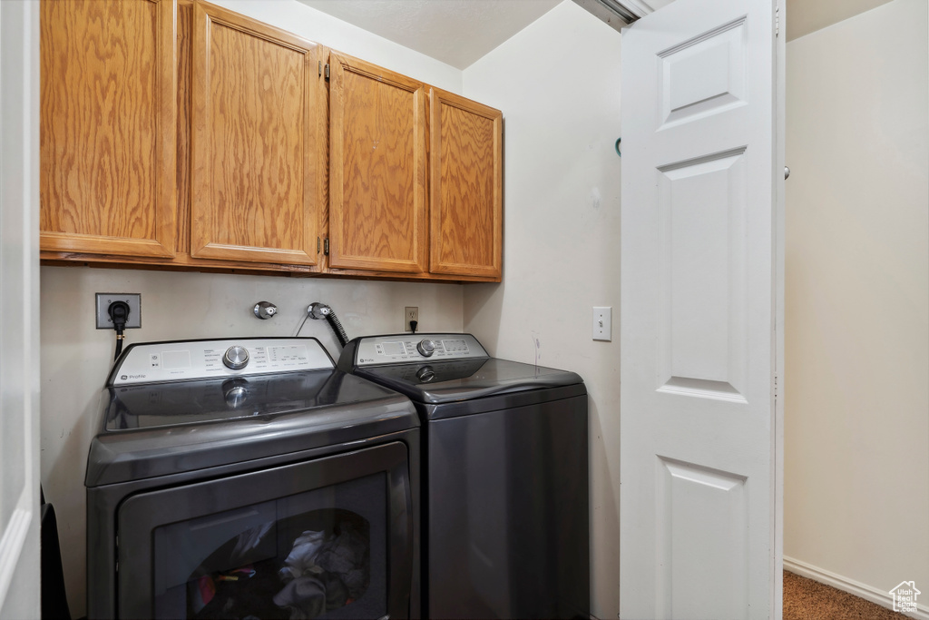 Washroom featuring cabinet space, separate washer and dryer, and carpet