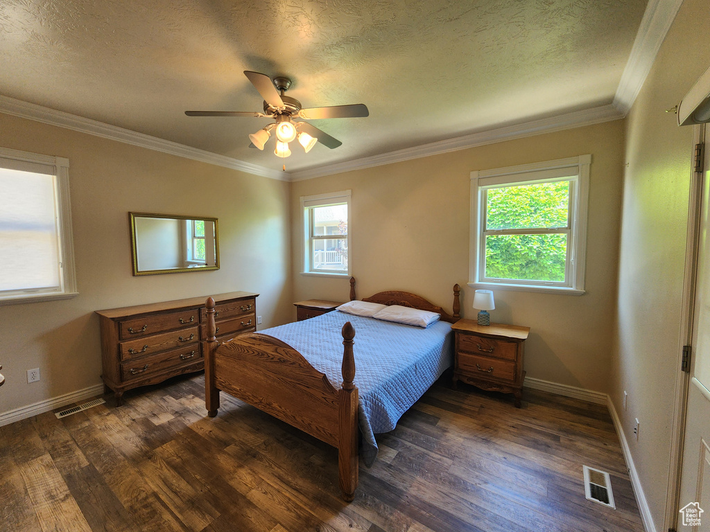 Bedroom featuring dark wood-style flooring, a textured ceiling, ornamental molding, baseboards, and ceiling fan