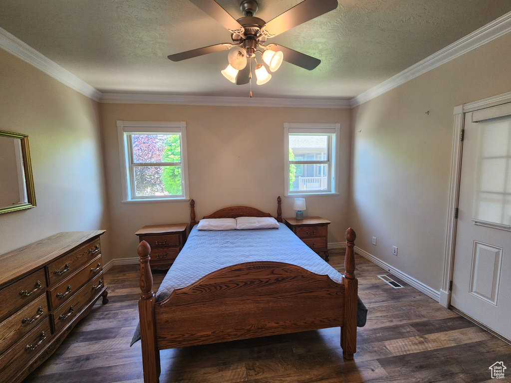 Bedroom featuring baseboards, dark wood-type flooring, ornamental molding, a textured ceiling, and a ceiling fan