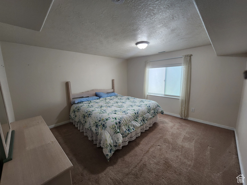 Bedroom with baseboards, carpet floors, and a textured ceiling