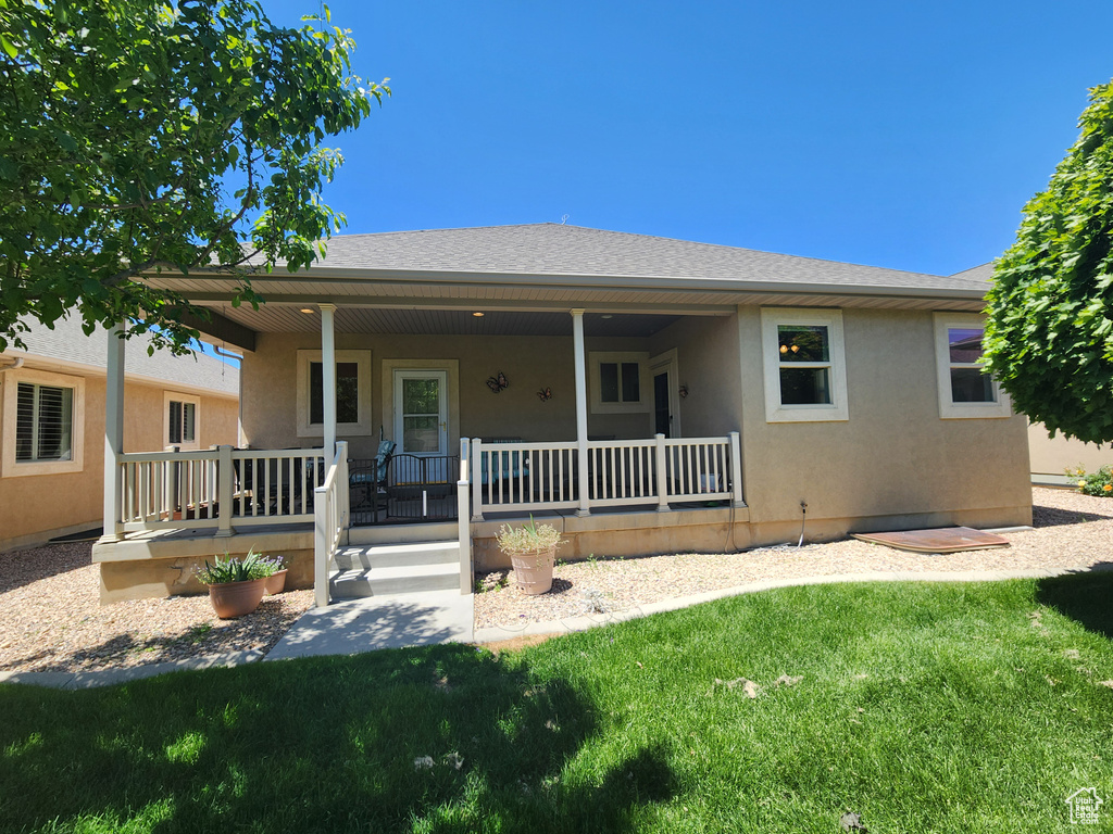 Ranch-style house with a porch, a front lawn, stucco siding, and a shingled roof