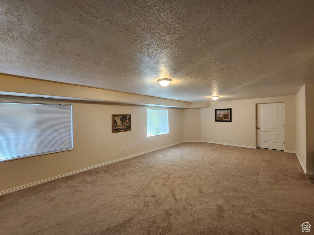 Carpeted empty room featuring a textured ceiling and baseboards