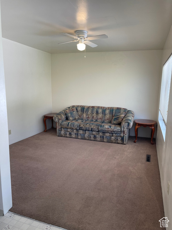 Living area with ceiling fan and light colored carpet