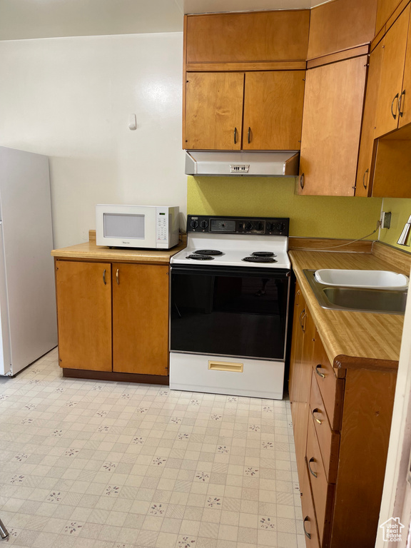 Kitchen featuring range with electric stovetop, white microwave, under cabinet range hood, and light floors