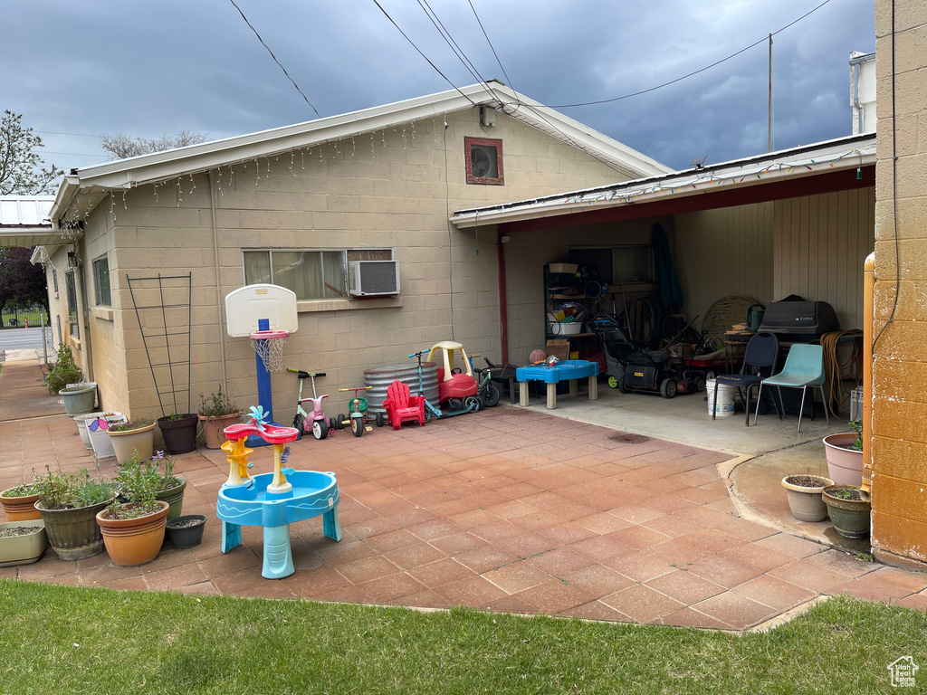 Back of property with a patio area, concrete block siding, and a wall unit AC