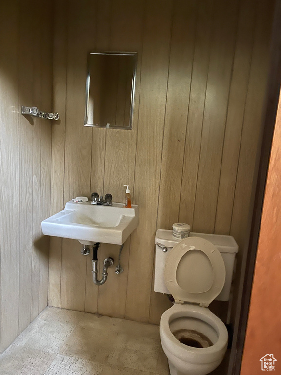 Half bath featuring toilet and wood walls