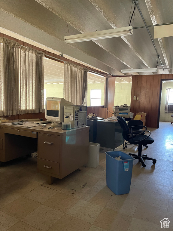 Misc room featuring a desk, light floors, and wood walls