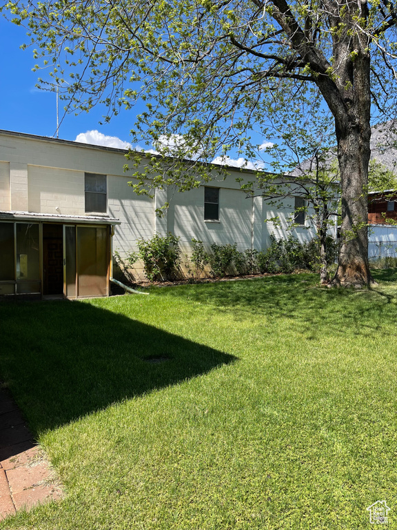 View of green lawn featuring a sunroom