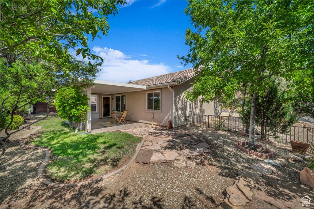 Rear view of house with stucco siding, a patio area, and a tile roof