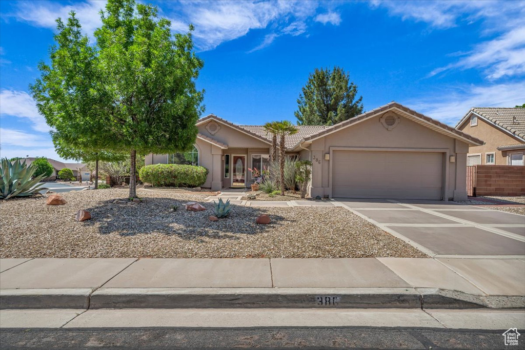 View of front of home with a garage, stucco siding, concrete driveway, and a tile roof