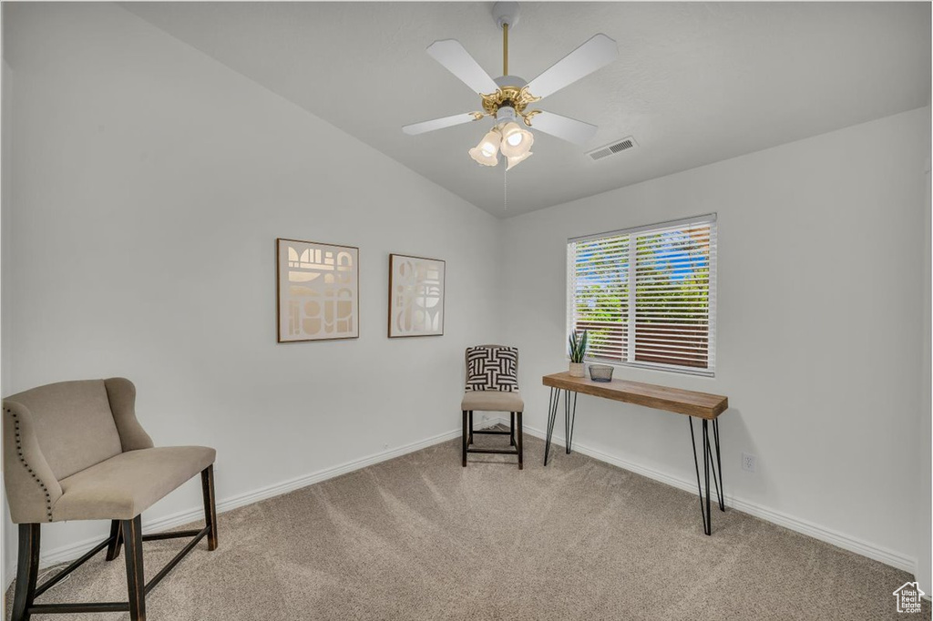 Living area with light carpet, vaulted ceiling, baseboards, and a ceiling fan