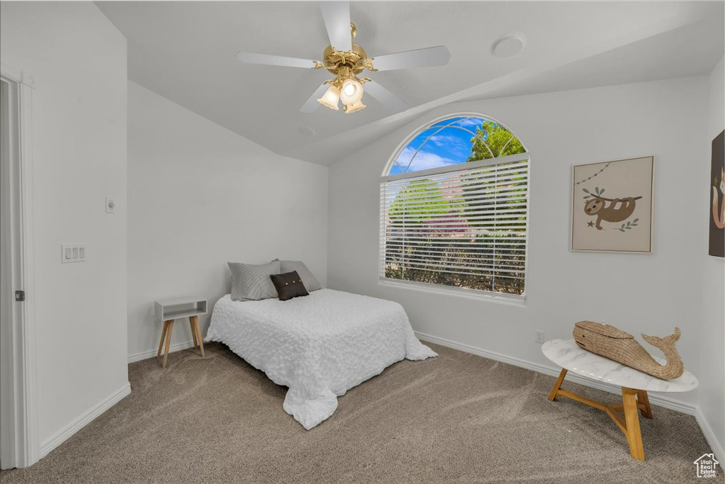 Carpeted bedroom featuring lofted ceiling, baseboards, and a ceiling fan