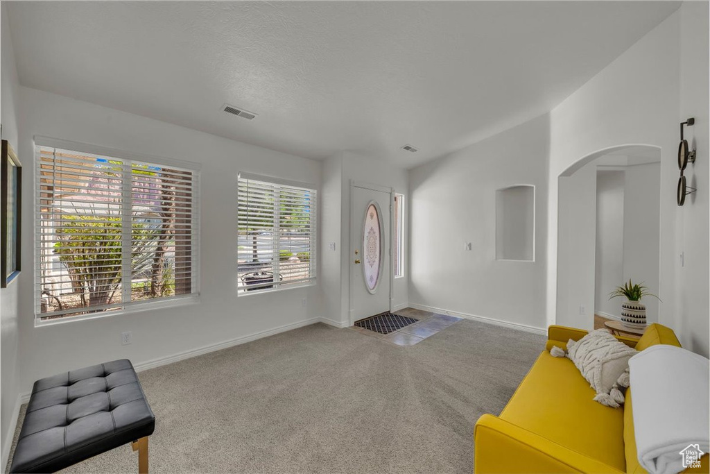 Carpeted foyer featuring arched walkways and baseboards